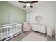 Cozy Bedroom with a white crib, pink rocking chair, and dresser, complemented by soft green and white walls at 5799 Boston St, Denver, CO 80238