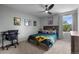 This bedroom features a sports theme with a bed, ceiling fan, window, and neutral carpet at 5010 Ox Trl, Parker, CO 80134