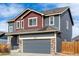 Two-story home featuring gray exterior, red accents, stone trim, and an attached garage at 6707 6Th St, Frederick, CO 80530