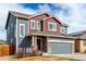 Two-story home showcasing gray exterior, red accents, stone trim, and a two-car garage at 6707 6Th St, Frederick, CO 80530