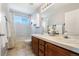 Bathroom featuring double sinks, wood cabinets, tiled floors, a tub, and a window at 9745 Hummingbird Pl, Littleton, CO 80125