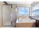 Bright bathroom featuring a large soaking tub, separate glass shower, and a window with mountain views at 9745 Hummingbird Pl, Littleton, CO 80125