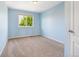 Bright bedroom with light blue walls, neutral carpet, and a window overlooking a lush green tree at 9745 Hummingbird Pl, Littleton, CO 80125