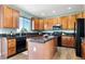 Kitchen with wood cabinets, black appliances, granite counters, and center island at 9745 Hummingbird Pl, Littleton, CO 80125