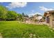 Expansive backyard with lush lawn, mature trees, stone patio, and outdoor dining area for relaxation and entertainment at 10380 W Warren Ave, Lakewood, CO 80227