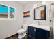 Modern bathroom with a navy vanity, sleek fixtures, and a Colorado themed art piece at 10380 W Warren Ave, Lakewood, CO 80227