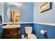 Stylish half bath with a wood vanity, round mirror and textured blue walls at 10529 Vaughn Way, Commerce City, CO 80022