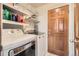 Laundry room with white washer and dryer, shelving, and a wooden door at 10529 Vaughn Way, Commerce City, CO 80022