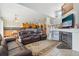 Open-concept living room with fireplace, tv, and leather couches that flows into the kitchen and dining area at 11416 E 114Th Ave, Commerce City, CO 80640