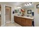 Bathroom featuring double sinks, wood cabinets, a large mirror, and decorative accents at 9546 Firenze Way, Highlands Ranch, CO 80126