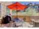 An outdoor patio includes comfortable seating under a bright umbrella and a small grill at 9546 Firenze Way, Highlands Ranch, CO 80126