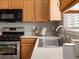 Kitchen featuring stainless steel stove, microwave, bright countertops, and stainless steel sink at 5115 S Valdai St, Aurora, CO 80015