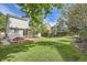 Large backyard with a manicured lawn, mature trees, a deck, and a privacy fence at 9661 Autumnwood Pl, Highlands Ranch, CO 80129
