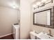 Bright bathroom featuring a modern vanity with sink, toilet, and washer/dryer at 9661 Autumnwood Pl, Highlands Ranch, CO 80129