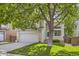 Two-story home with a grey garage door, brick accents, and beautiful tree shading the well kept lawn at 9661 Autumnwood Pl, Highlands Ranch, CO 80129