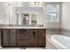 Bright bathroom featuring a double sink vanity with dark cabinets, and a separate bathtub with stylish mosaic tile accents at 540 E Fremont Pl, Centennial, CO 80122