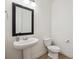 Neat powder room featuring pedestal sink, dark framed mirror, and neutral color palette at 14423 Shasta Daisy Ln, Parker, CO 80134