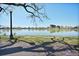 Scenic view of a calm lake bordered by lush green grass and shaded by mature trees under a clear sky at 1027 S University Blvd, Denver, CO 80209