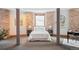 Spacious bedroom featuring exposed brick, neutral walls, columns, and modern furniture at 3249 W Fairview Pl # 106, Denver, CO 80211