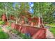 Beautiful backyard view featuring vibrant purple flowers, mature trees, and a charming red fence at 23626 Genesee Village Rd, Golden, CO 80401