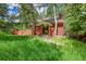 Inviting red home with lush trees, a landscaped front yard, and a pathway to the charming front entrance at 23626 Genesee Village Rd, Golden, CO 80401