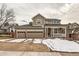 Charming two-story home with a three-car garage and a covered front porch with snow at 240 Corby Pl, Castle Pines, CO 80108