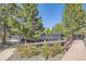 Outdoor tennis court featuring a wooden fence, surrounded by lush green trees and rocks at 240 Corby Pl, Castle Pines, CO 80108