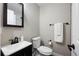 Cozy bathroom featuring a dark vanity, toilet, and mirror with a white towel on the rack at 991 E Applewood Ave, Centennial, CO 80121