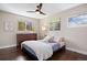 Cozy bedroom with a comfortable bed, natural lighting from two windows, ceiling fan, and a wooden dresser at 991 E Applewood Ave, Centennial, CO 80121