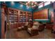 Elegant home office with wood bookshelves, cabinetry, desk, comfortable chairs, and chandelier at 703 Emberglow Ln, Highlands Ranch, CO 80126