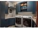 Well-equipped laundry room with modern washer, dryer, sink, and built-in storage cabinets at 703 Emberglow Ln, Highlands Ranch, CO 80126