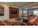 Cozy living room with stone accent wall, TV, comfortable leather seating, and outdoor view at 703 Emberglow Ln, Highlands Ranch, CO 80126