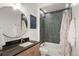 Bathroom with granite countertop vanity, round mirror, tiled shower with tub, and neutral color scheme at 1242 Yates St # U2, Denver, CO 80204