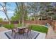 Landscaped backyard featuring outdoor seating area, lush lawn, privacy fence, and mature trees at 7061 Palisade Dr, Highlands Ranch, CO 80130