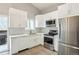Bright kitchen featuring white cabinetry, stainless appliances, mosaic backsplash, and access to outdoor deck at 7061 Palisade Dr, Highlands Ranch, CO 80130