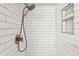 Close-up of shower featuring white subway tile, bronze shower head, and convenient inset shelving at 7061 Palisade Dr, Highlands Ranch, CO 80130