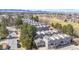 Aerial view of gray townhomes with a golf course and a mountain range in the background on a sunny day at 6725 W 84Th Way # 67, Arvada, CO 80003