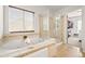 Bathroom featuring a jacuzzi tub, glass shower, neutral colors, and tiled floors at 132 Mesa St, Brighton, CO 80601