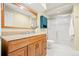 Bright bathroom featuring wood vanity, granite counters, tiled floors, and glass-enclosed shower at 132 Mesa St, Brighton, CO 80601