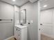 Bathroom with a stylish vanity, modern fixtures, black framed mirror, and a doorway with a white door at 12018 Hudson Ct, Thornton, CO 80241