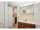 Cozy bathroom with a wood vanity, white countertop, and an adjacent closet for storage at 1118 Eagle Rd, Broomfield, CO 80020