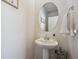 Half bathroom with a pedestal sink and stylish round mirror and fresh white paint at 700 Lillibrook Pl, Erie, CO 80026