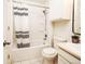 Bright bathroom featuring a tub with striped shower curtain, vanity with sink, and commode at 13894 E Lehigh Ave # G, Aurora, CO 80014