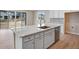 Kitchen island with white cabinets, quartz countertop, and a farmhouse sink at 3432 N Gold Bug Ct, Aurora, CO 80019