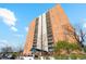 A tall brick apartment building stands under a blue sky with minimal landscaping around the entrance at 955 Eudora St # 801E, Denver, CO 80220