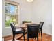 Bright dining area featuring a wood table, four black chairs, and a large window overlooking the lush outdoors at 4085 S Crystal Cir # 104, Aurora, CO 80014