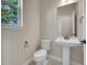 Powder room featuring a pedestal sink, toilet, and window at 17186 E Cedar Gulch Dr, Parker, CO 80134