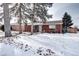 Brick ranch home with snowy front yard and mature trees at 2391 Lansing St, Aurora, CO 80010