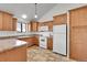Bright kitchen with wooden cabinets, white appliances, and a window providing natural light at 7077 S Bryant St, Littleton, CO 80120