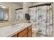 Bathroom featuring wood cabinetry, tile countertops, patterned shower curtain, and neutral walls at 1127 Buttermilk Rd, Larkspur, CO 80118